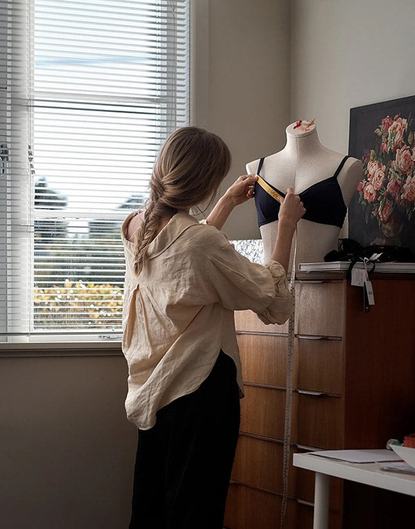 A woman working on a mannequin in front of a window.