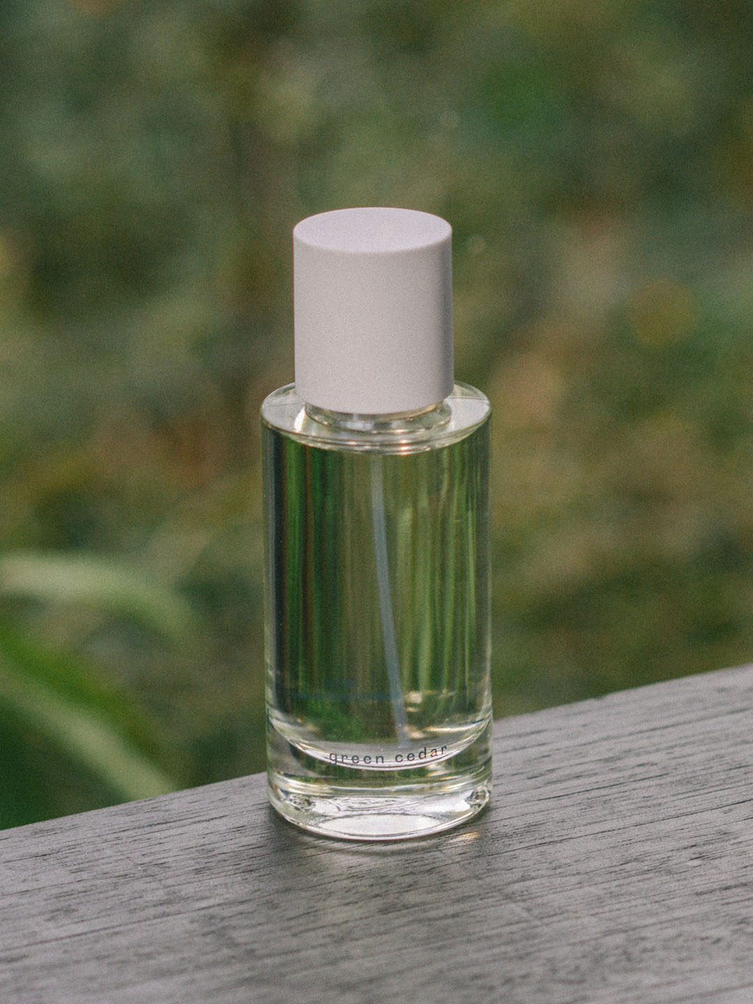 A bottle of Green Cedar – velvety, rich wood eau de parfum by Abel, made with Atlas Mountain cedar, sitting on a wooden table.
