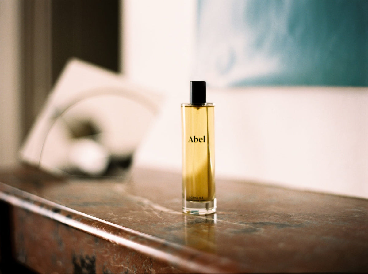 A bottle of Abel Room Spray – Scene 03, crafted with leather, tonka, and vanilla on a weathered surface with a soft-focused background.