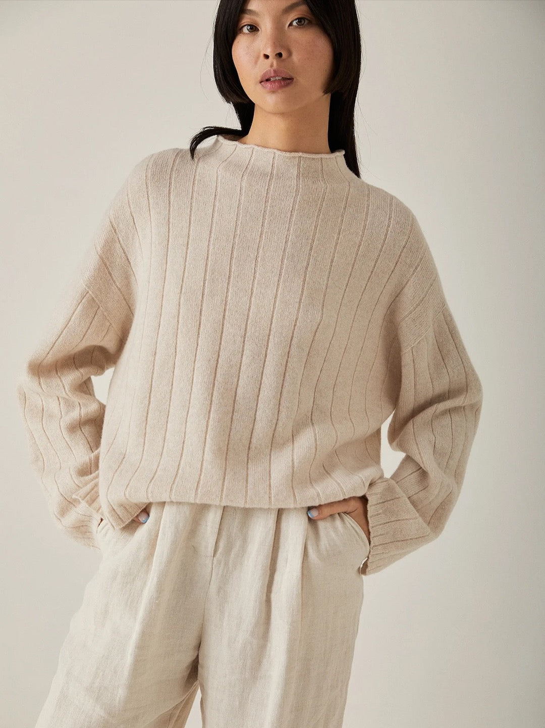 The model is wearing an oversized Francie Echo Knit - Creme sweater and white pants.