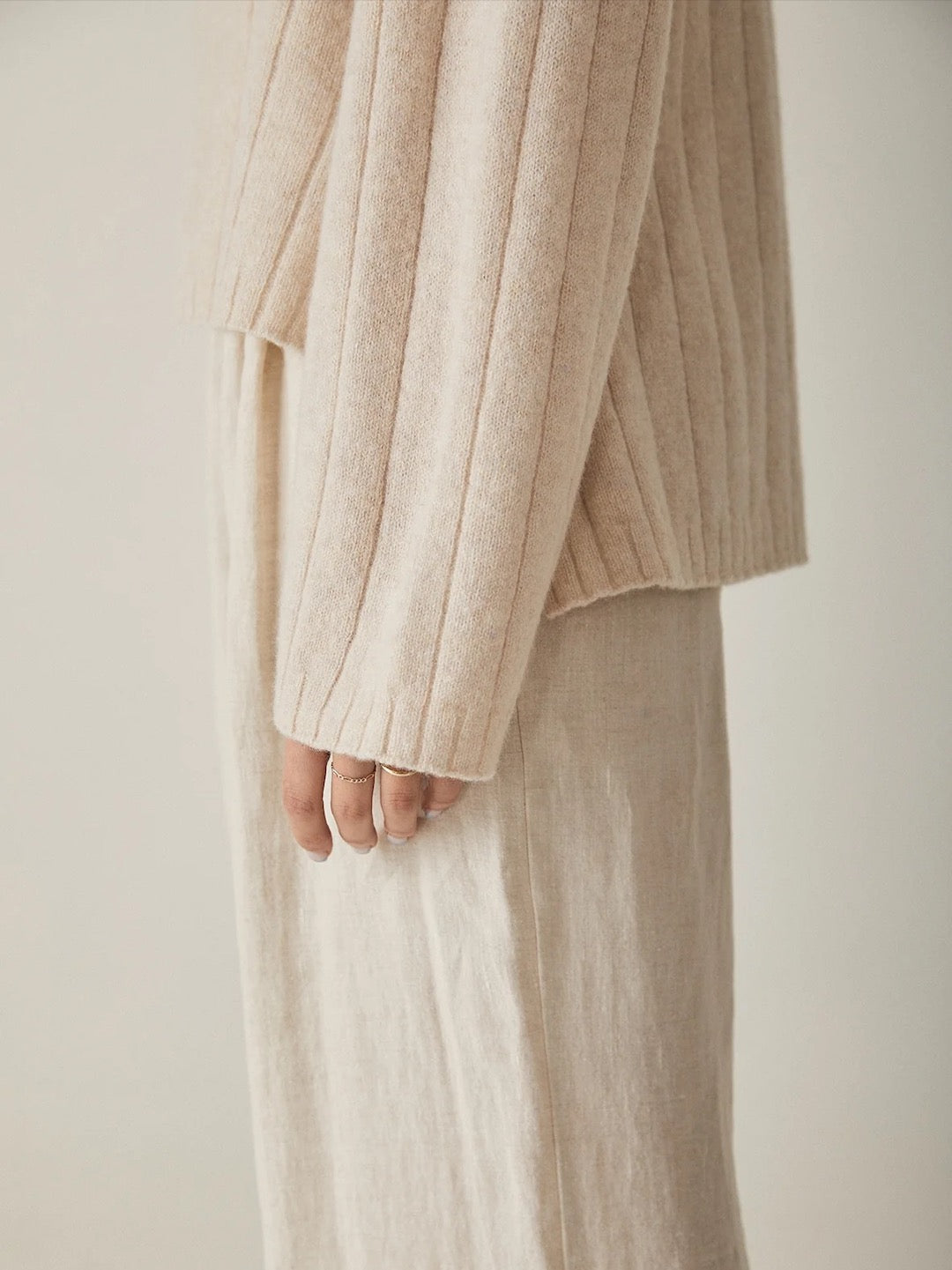 A woman wearing an oversized beige Echo Knit sweater and pants, featuring Italian air-spun merino with ribbing by Francie.