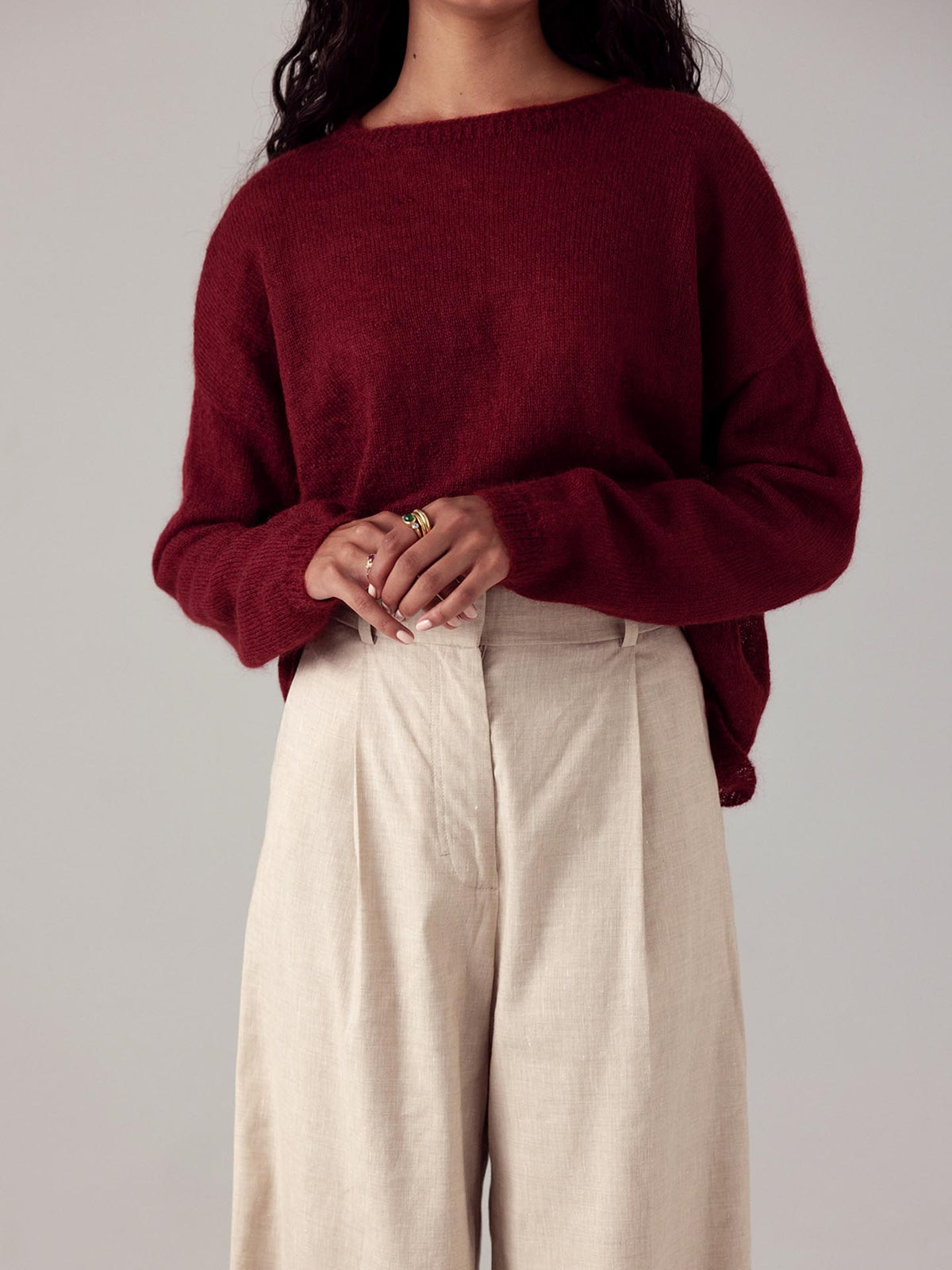 The model is wearing a Dark Cherry feather knit sweater by Francie and beige wide-leg pants.