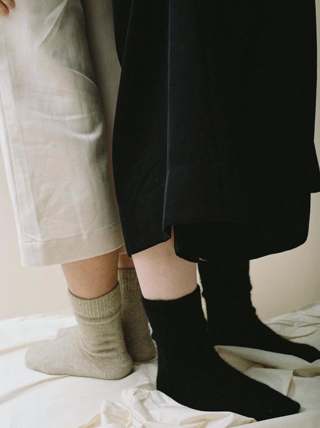Two people standing side by side in New Zealand, with the camera focused on their lower half, wearing different colored Francie Possum Merino socks and pants.