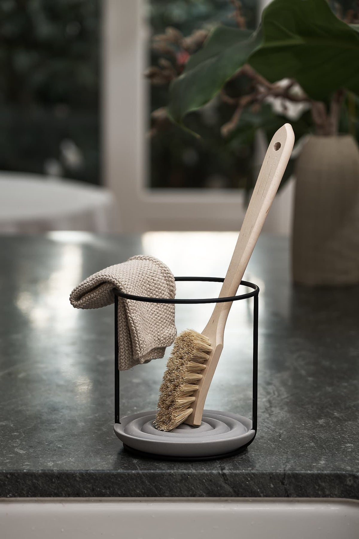 An Iris Hantverk Dish Brush Holder on top of a kitchen bench.