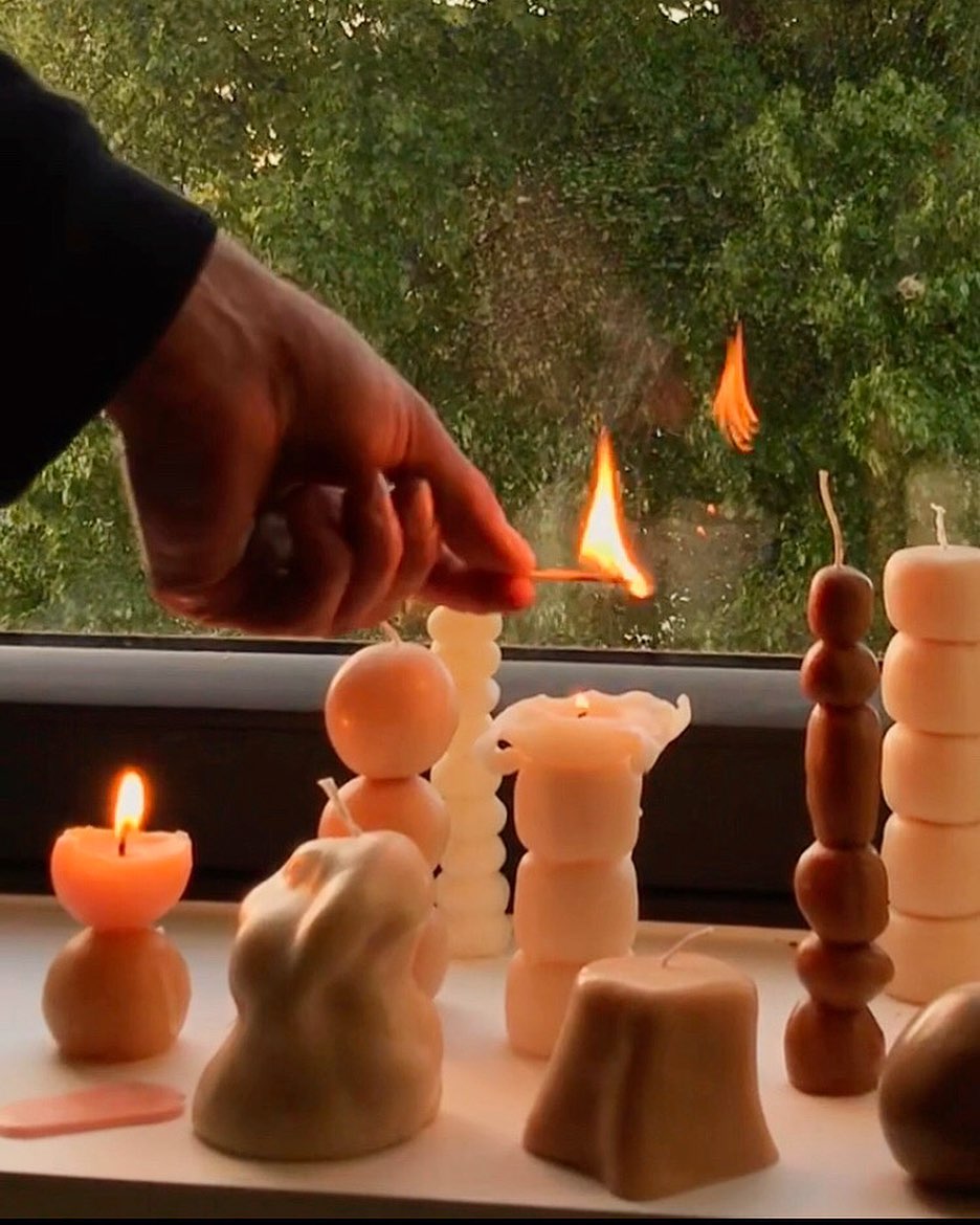 A person lighting Sole Set candles in front of a window by ann vincent.