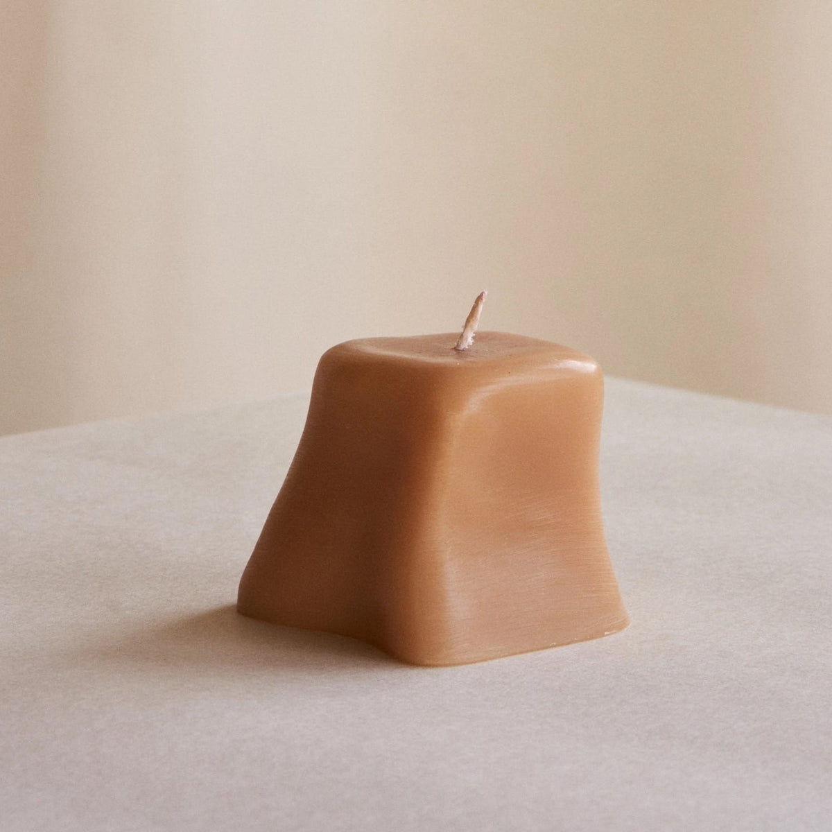 An ann vincent Sole Set candle sitting on a table with a beige background.