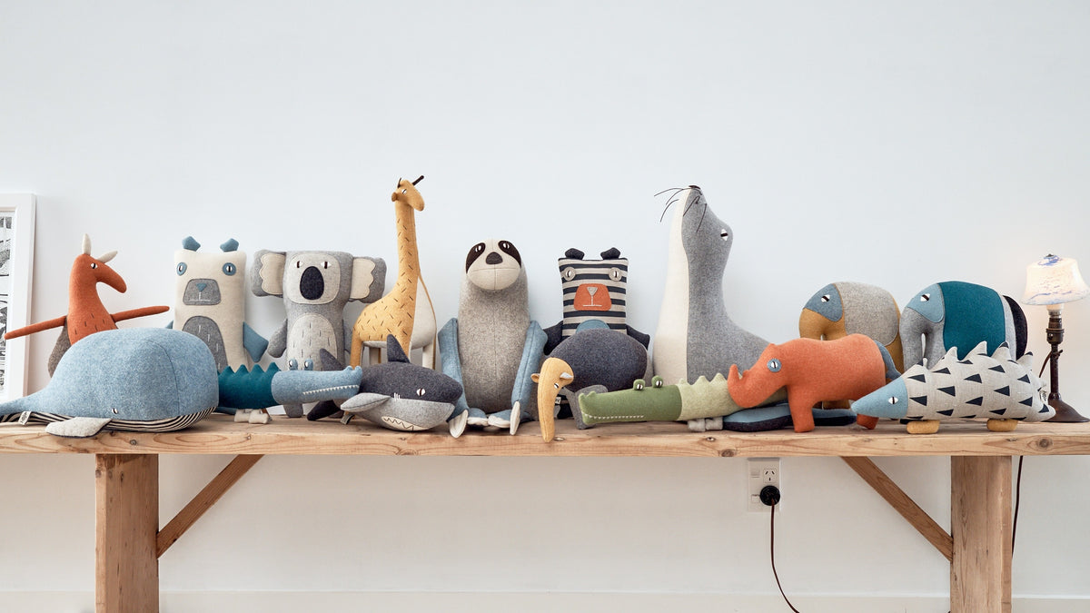 A group of BEN, the Great White Shark stuffed animals on a wooden table. Brand: Carapau