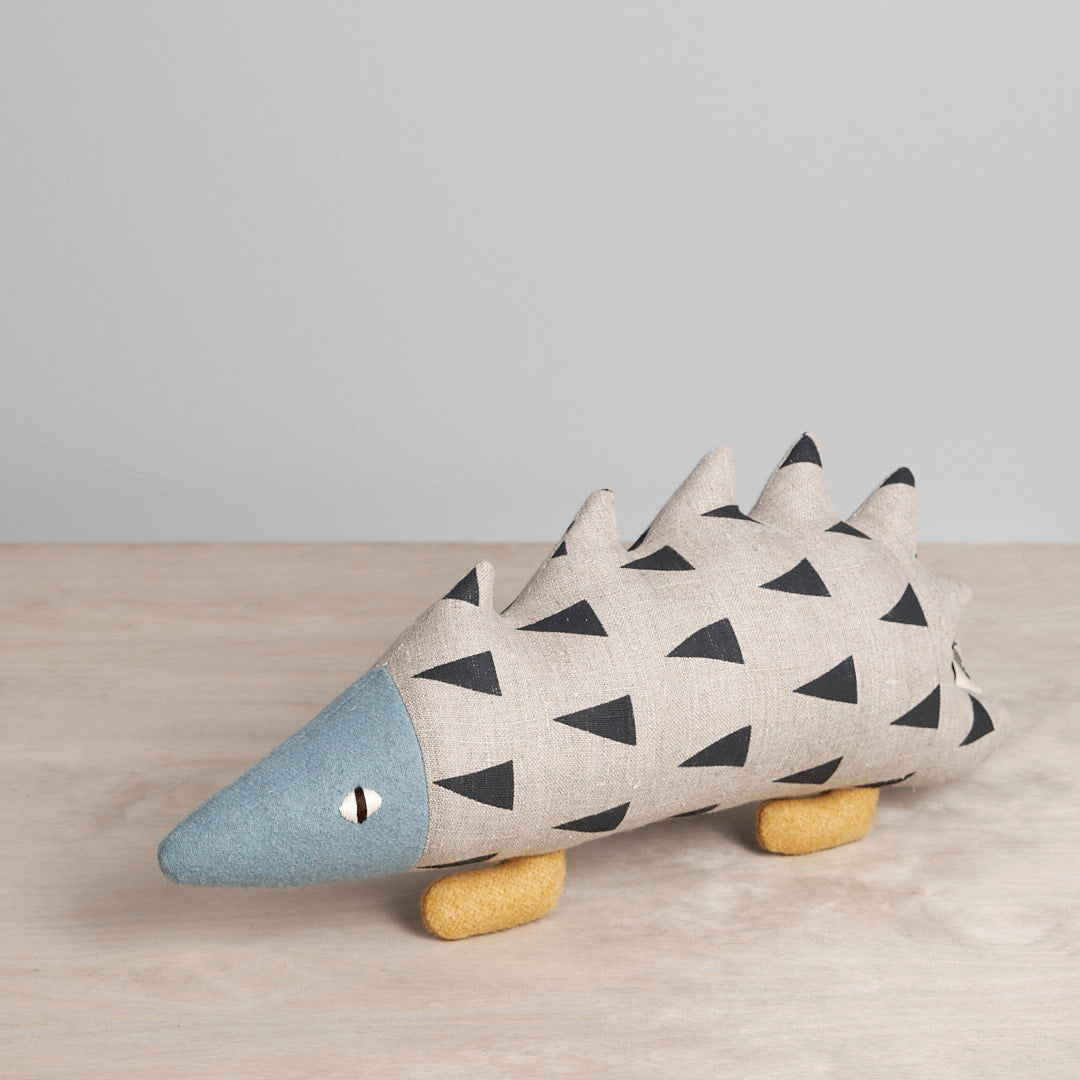 A JIN, the Amur Hedgehog stuffed animal on a wooden table by Carapau.