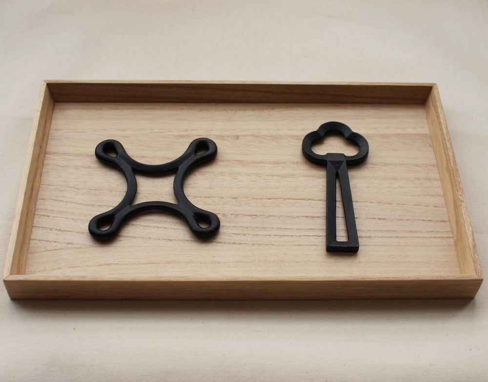 A Clover Bottle Opener – Rusty Brown by Chushin Kobo tray with a black key and a pair of scissors.