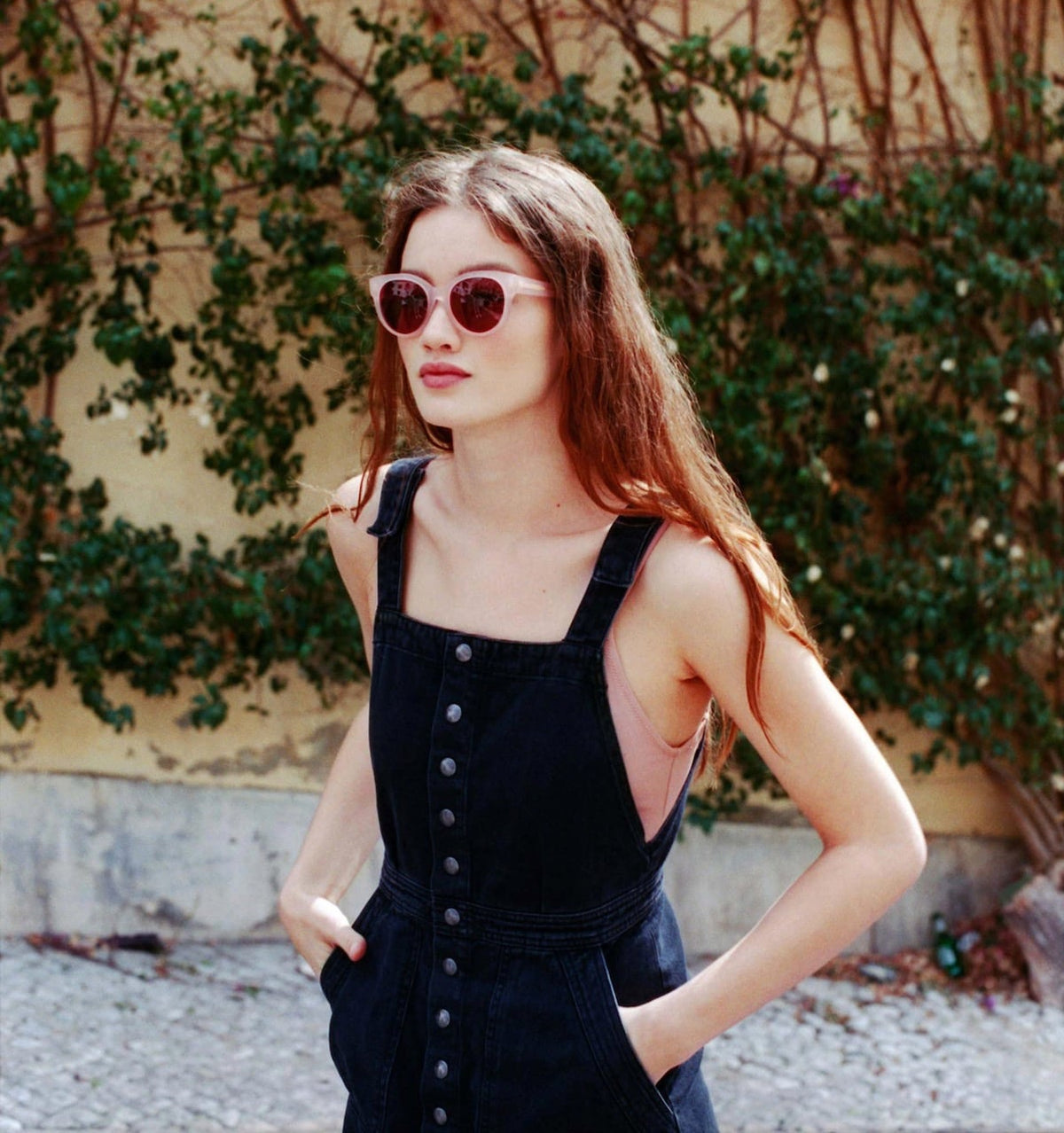 A woman in a black overall dress wearing Dick Moby&#39;s Paris Sunglasses – Pale Rose.