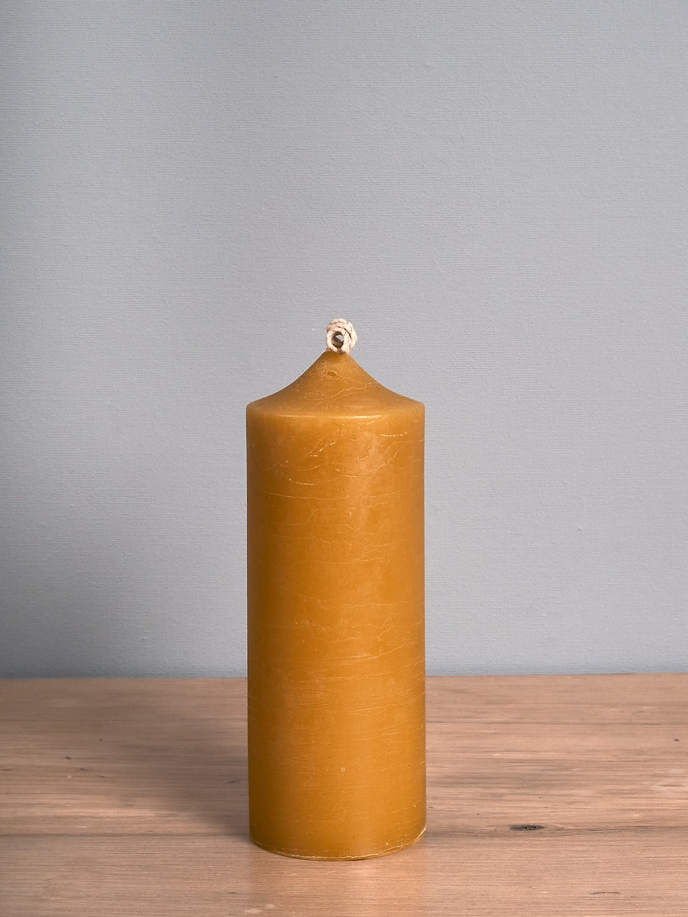 A Cafe Candle – Tall by Hohepa Candles is sitting on a wooden table.