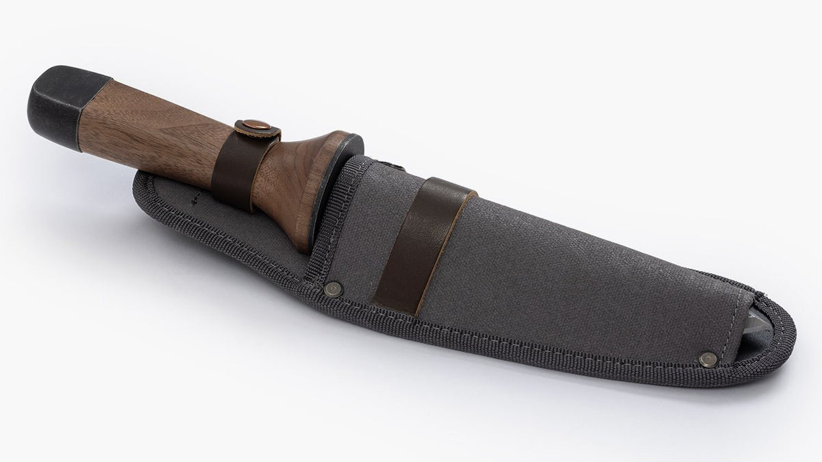 A Hori Hori Garden Knife &amp; Sheath with a leather sheath on a white surface. (Brand: Barebones)