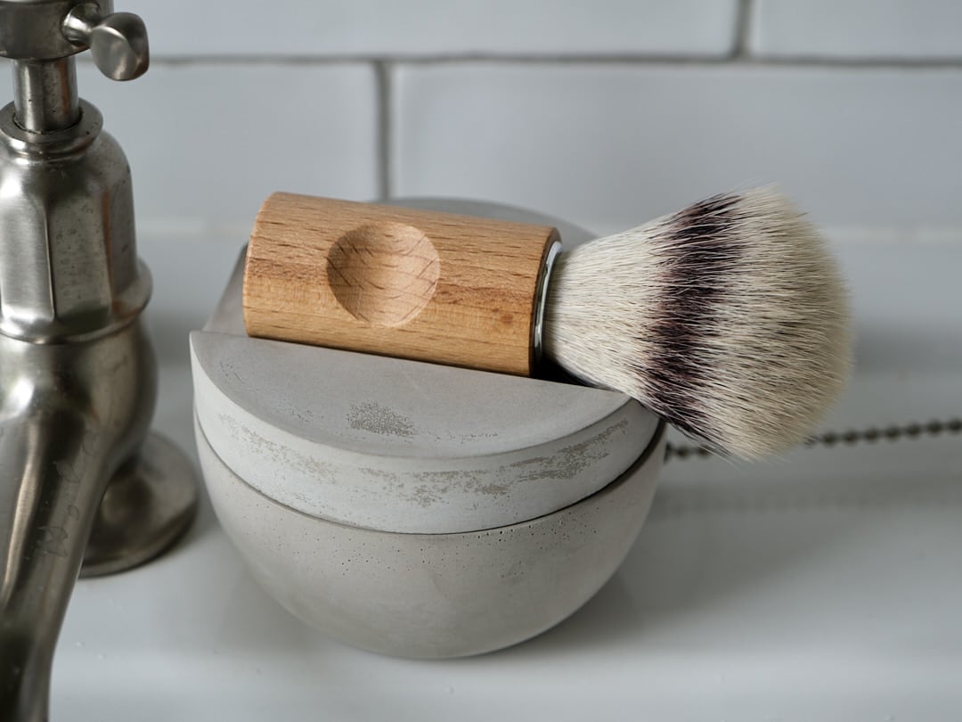 An Iris Hantverk wooden Shaving Brush &amp; Cup with Cedarwood Soap sits on top of a sink.