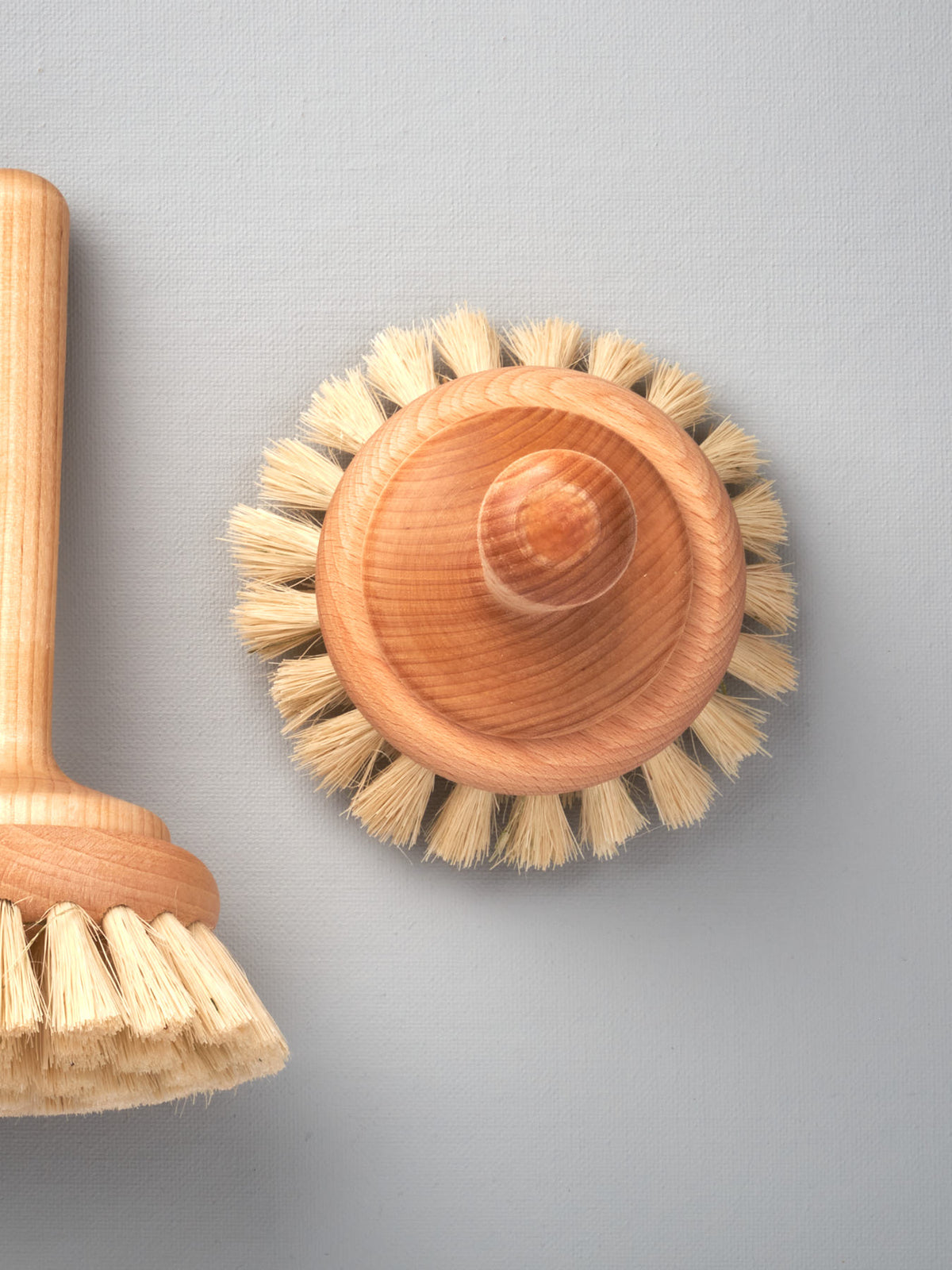 Two Iris Hantverk bathroom cleaning brushes on a gray background.