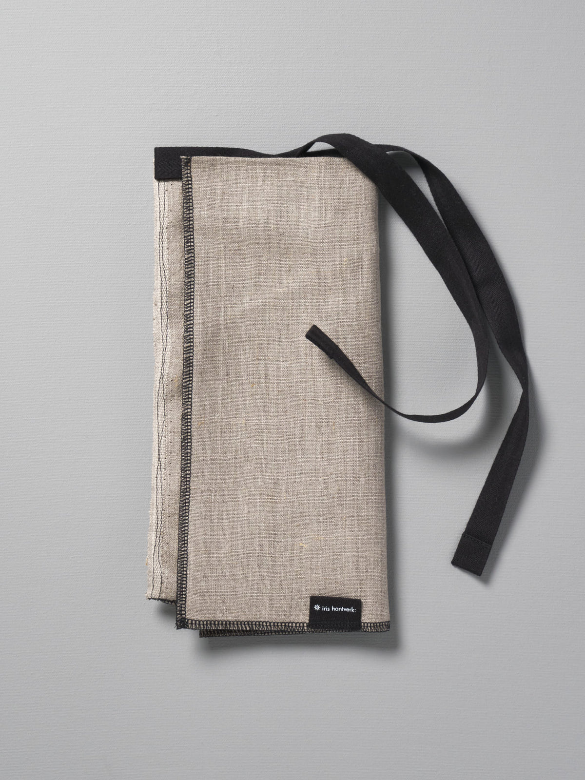 A Iris Hantverk Bread Bag – Linen with a black strap.