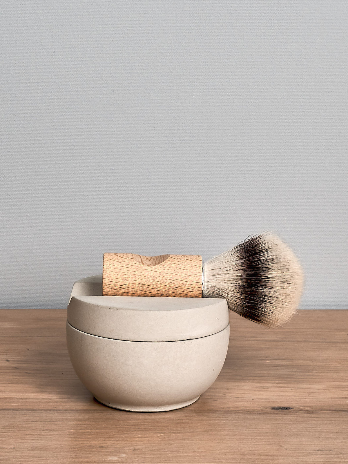 An Iris Hantverk Shaving Brush &amp; Cup with Cedarwood Soap sits on top of a wooden bowl.