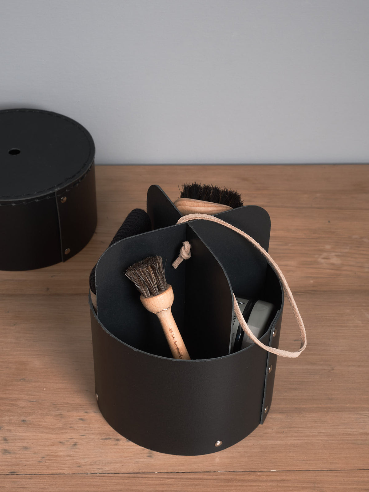 A black Shoe Care Kit with a brush and a brush holder by Iris Hantverk.