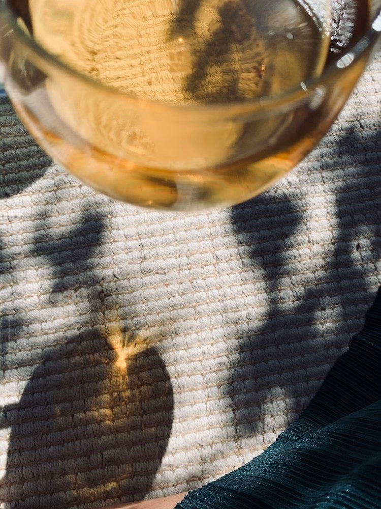 A glass of Kūmarahou Calm by Kaputi Studio on a table with a shadow.