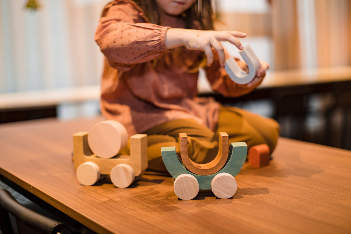 A little girl playing with MinMin Copenhagen Balancing Car on a table.