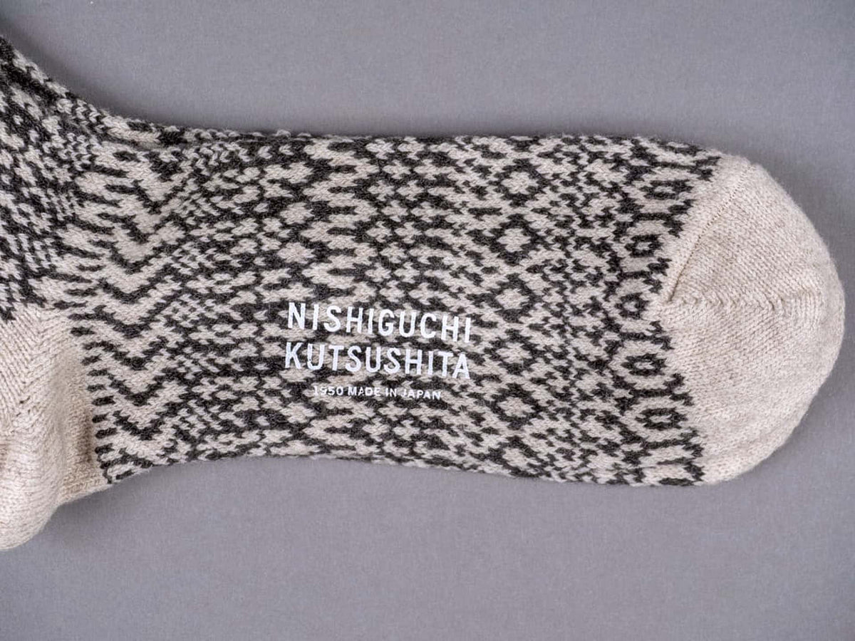 A pair of Nishiguchi Kutsushita Oslo Wool Jacquard Socks – Oatmeal with a logo on them.