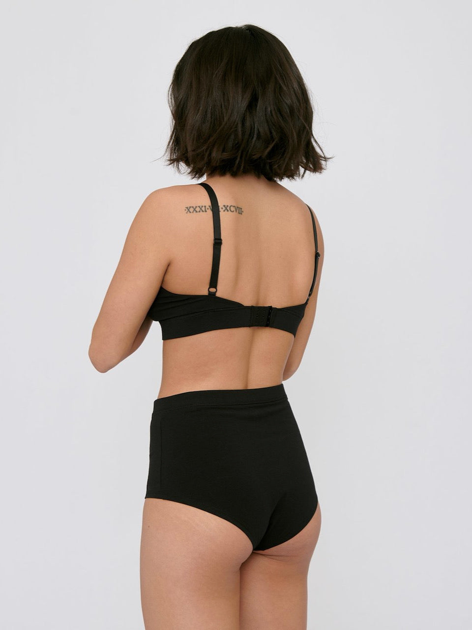 The back view of a woman wearing Organic Basics&#39; Super High-Rise Briefs ⋅ organic cotton – (2-pack) – Black.