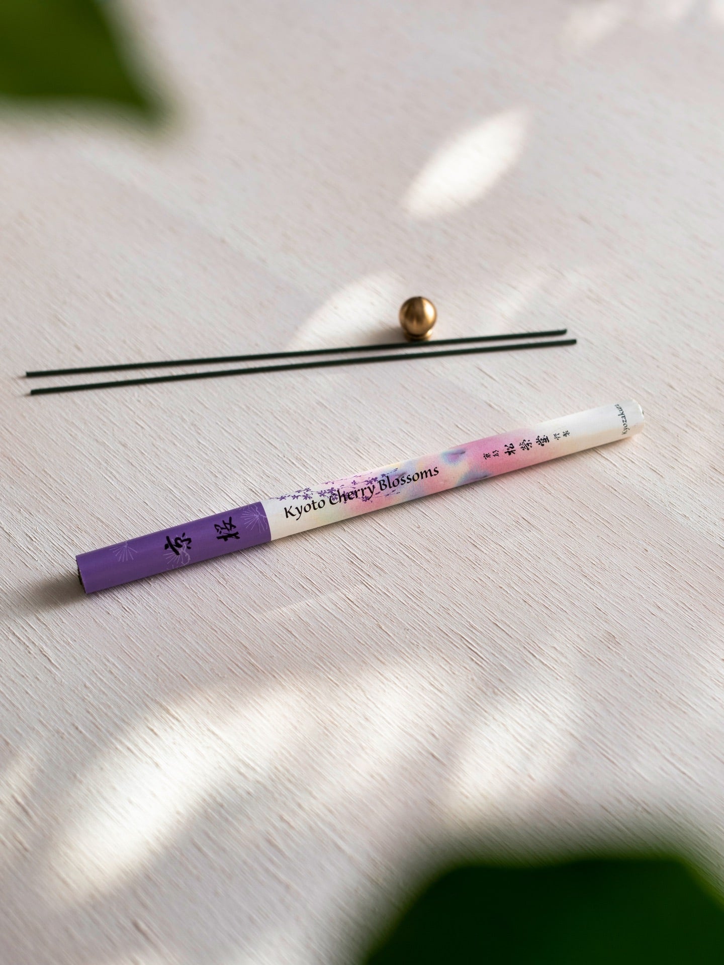 A Cherry Blossom – Kyozakura pencil with a purple flower on it next to a plant. (Brand: Senko)