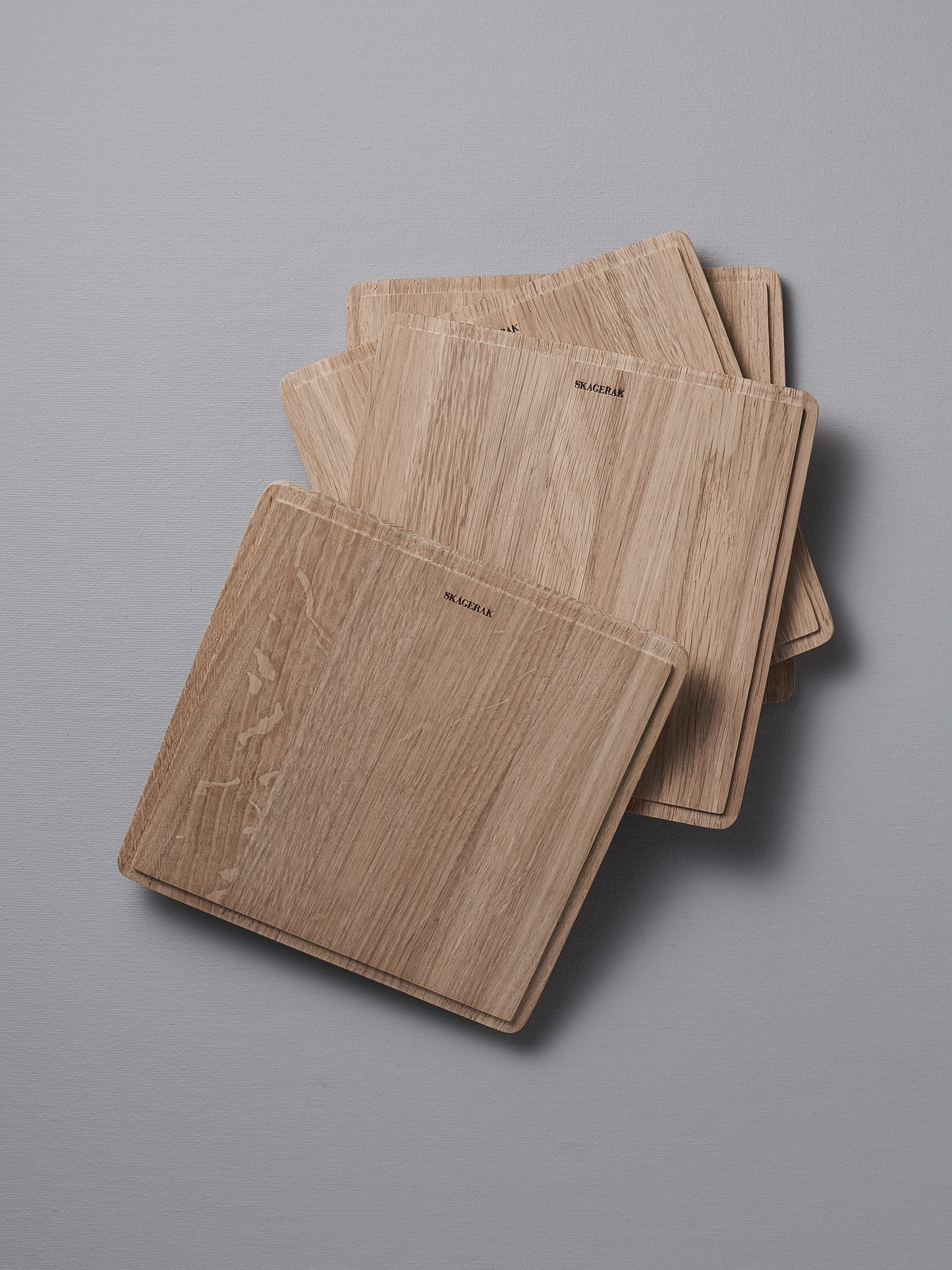 Four Skagerak Plank Square Trencher 4pcs - Oak cutting boards on a grey surface.