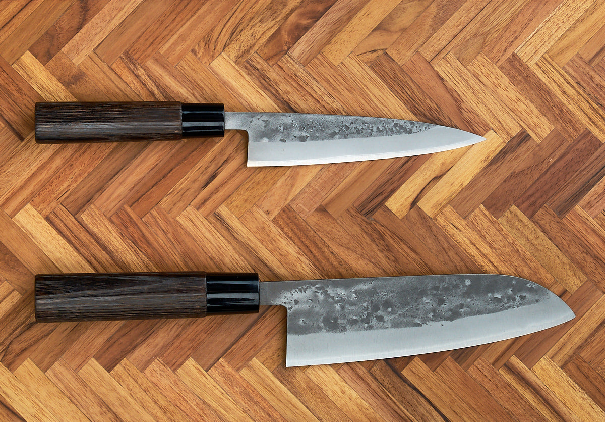 A Tadafusa Bocho Santoku Knife placed on a wooden surface, designed for all purpose use with a focus on vegetables.