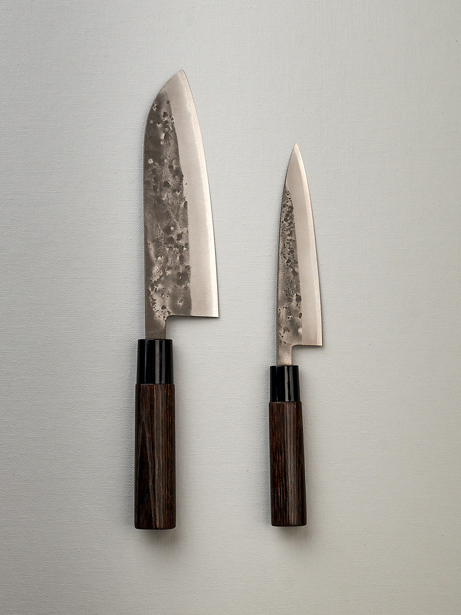 Two Tadafusa Bocho Santoku knives on a white surface next to each other, perfect for all purpose use and vegetable focus.