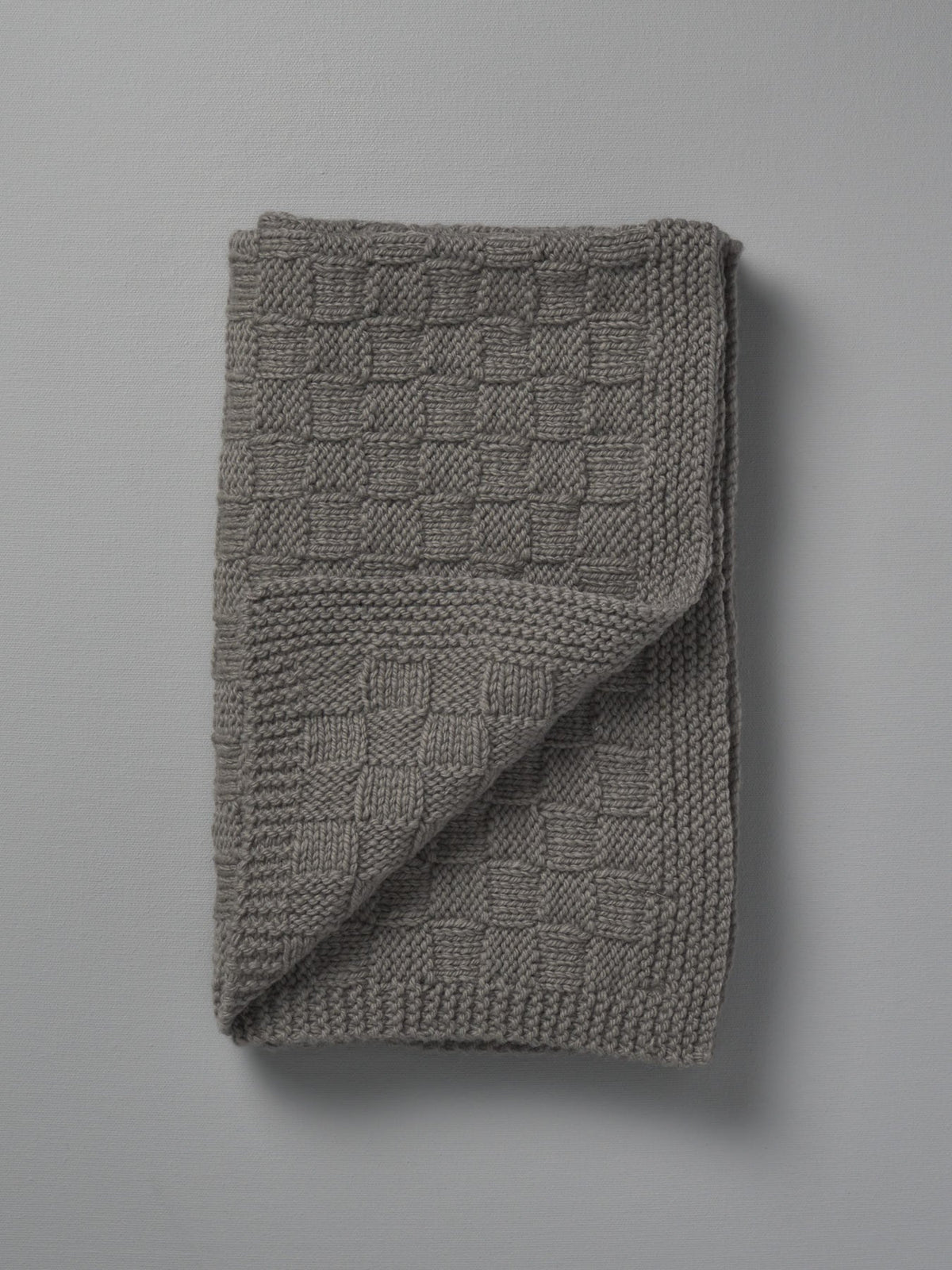 A grey Weebits Hand Knitted Travel Rug - Mushroom on a grey background.