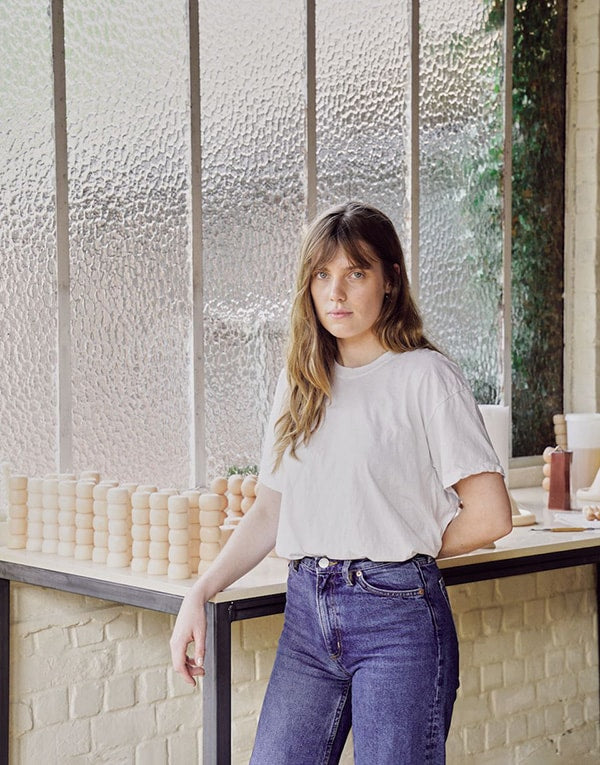 A woman wearing jeans and a t - shirt standing in front of a window.