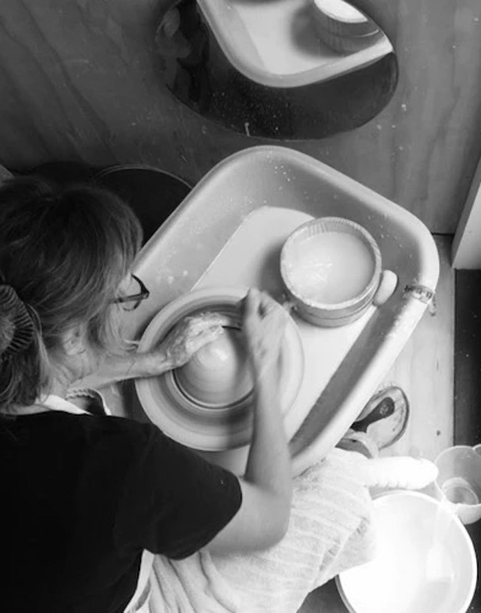 A black and white photo of a woman making pottery.
