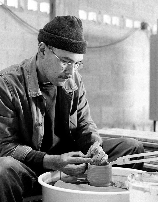 A man in a beanie working on a pot.