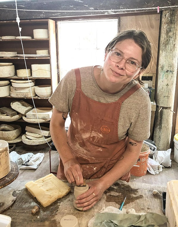 A woman in an apron is working in a pottery studio.