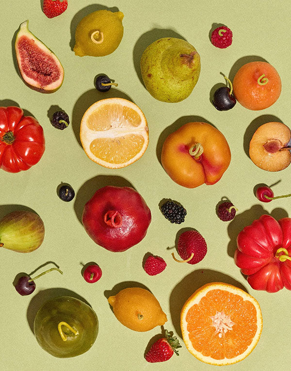 Various fruits, including figs, oranges, pears, lemons, tomatoes, berries, and cherries, are arranged on a light green background.