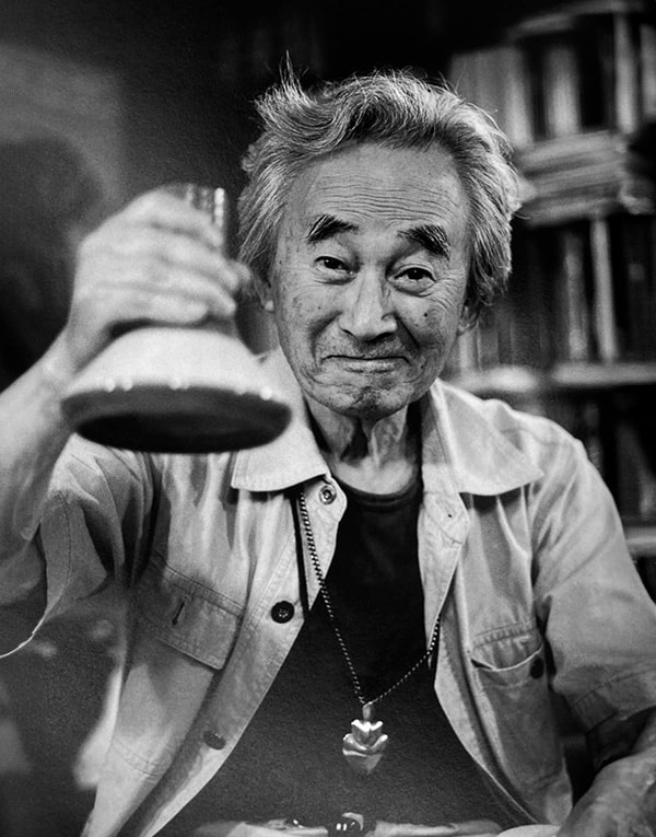 A black and white photo of an old man holding a glass.