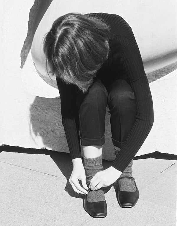 A woman is tying her shoes.
