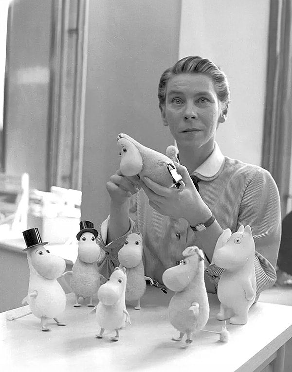 A woman is holding a group of stuffed animals.