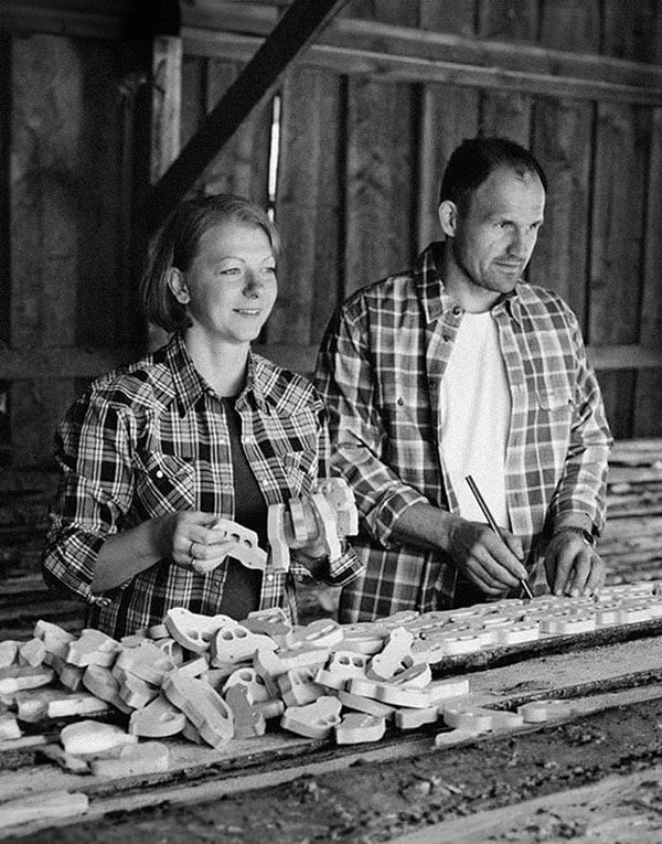 Two people in plaid shirts working with wood in a workshop.