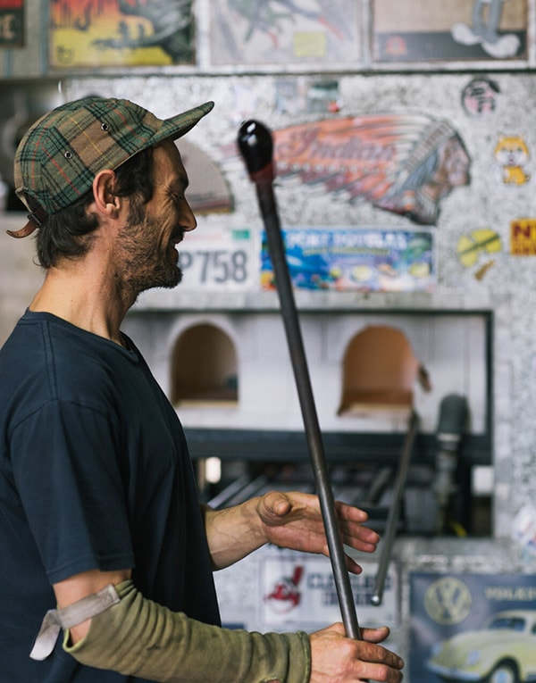 A man holding a baseball bat in a workshop.
