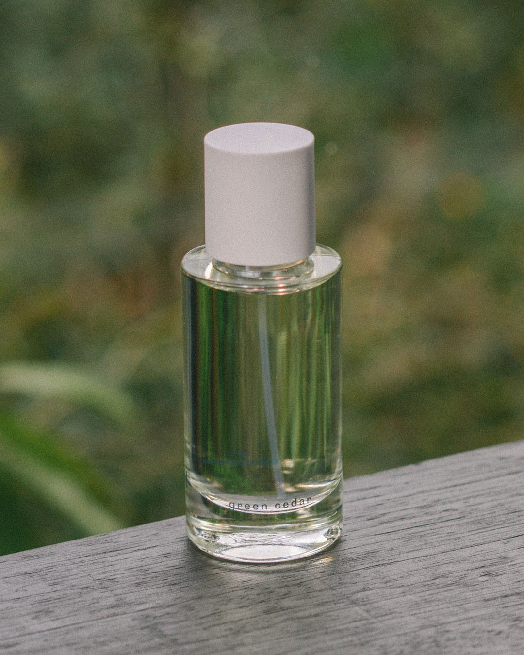 A bottle of Green Cedar – velvety, rich wood eau de parfum by Abel, made with Atlas Mountain cedar, sitting on a wooden table.