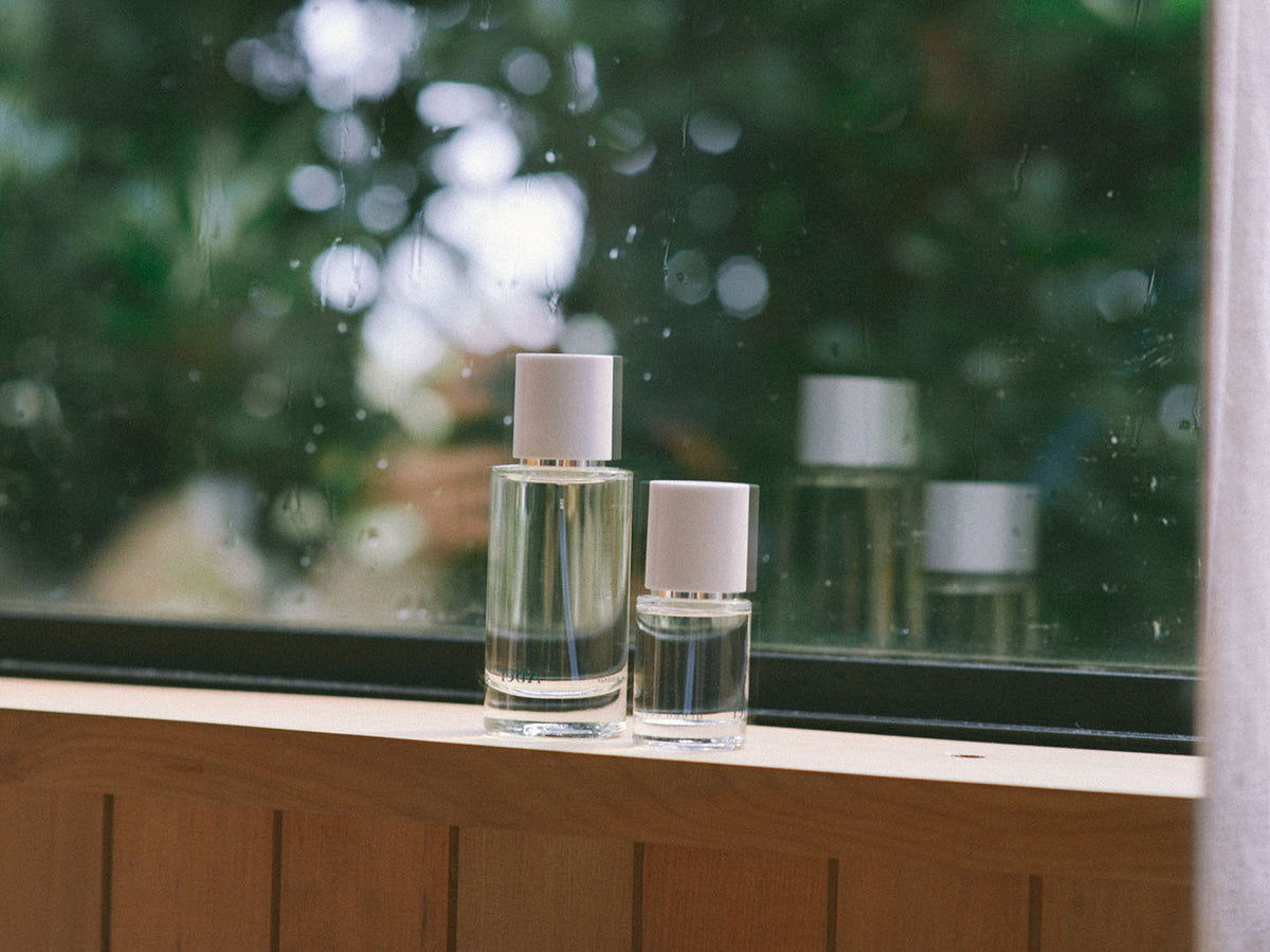 Two bottles of Abel&#39;s Green Cedar – velvety, rich wood eau de parfum, one scented with Texas cedar and the other with Atlas Mountain cedar, sitting on a window sill.