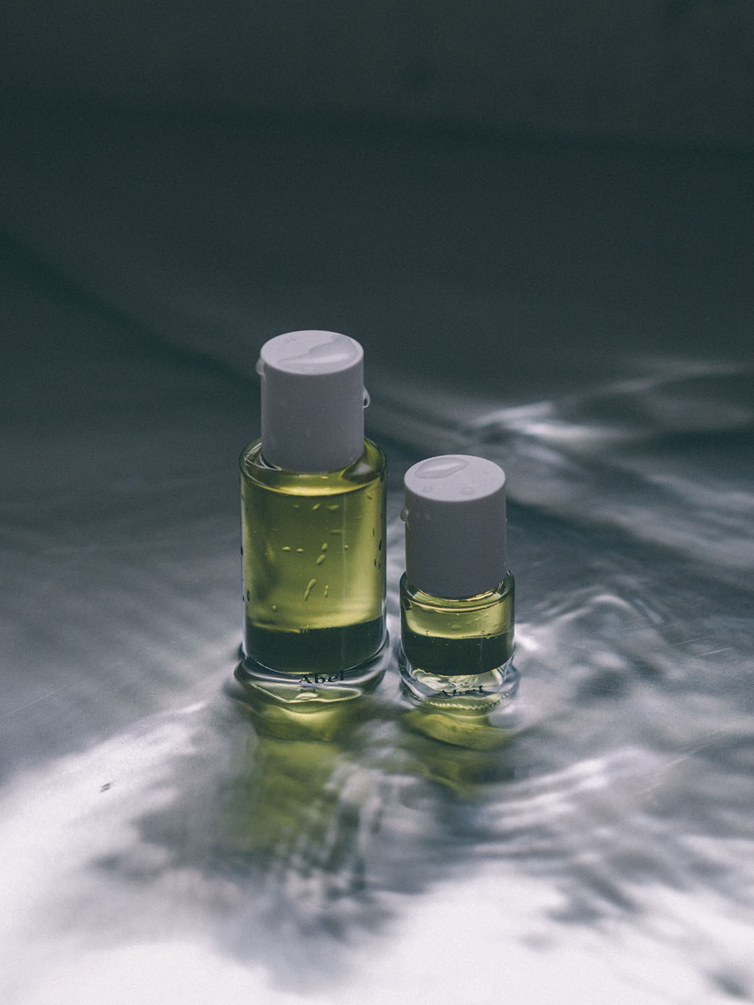 Two bottles of Abel's Cyan Nori – a sweet, salty musk eau de parfum sitting on top of water.