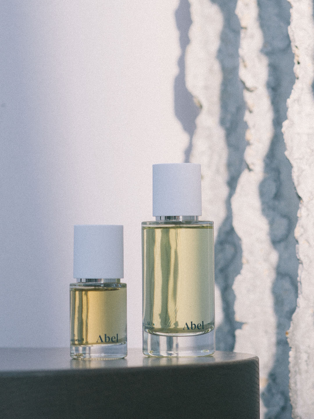 Two bottles of White Vetiver perfume by Abel on a ledge with a textured wall in the background, featuring natural eau de parfum.
