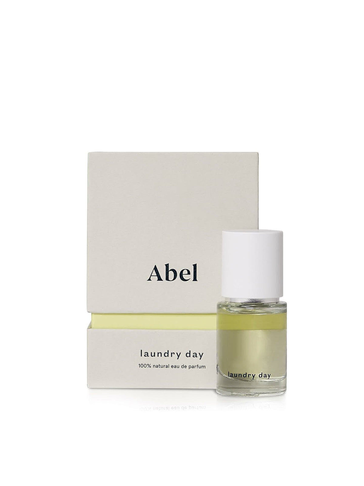 A small bottle of ethically sourced perfume labeled &quot;Laundry Day – a verdant, sun-filled citrus&quot; sits in front of a matching rectangular box labeled &quot;Abel.&quot; The liquid inside the bottle is yellow-green.