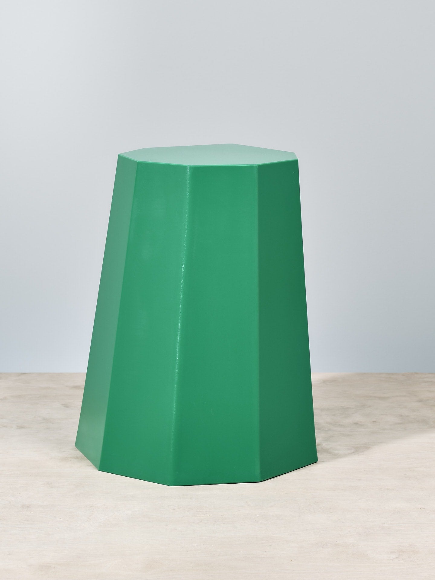 A Martino Gamper Arnold Circus Stool - Bright Green on top of a wooden floor.