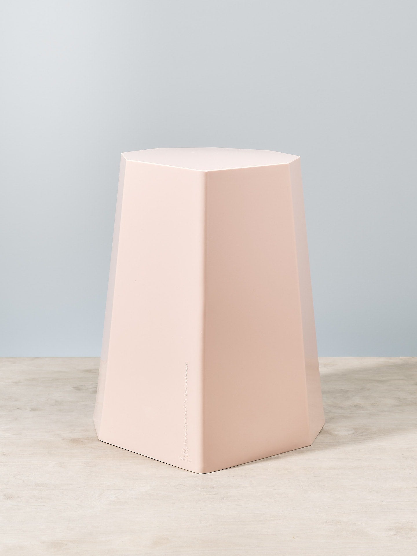An Arnold Circus Stool - Pink by Martino Gamper on top of a wooden table.
