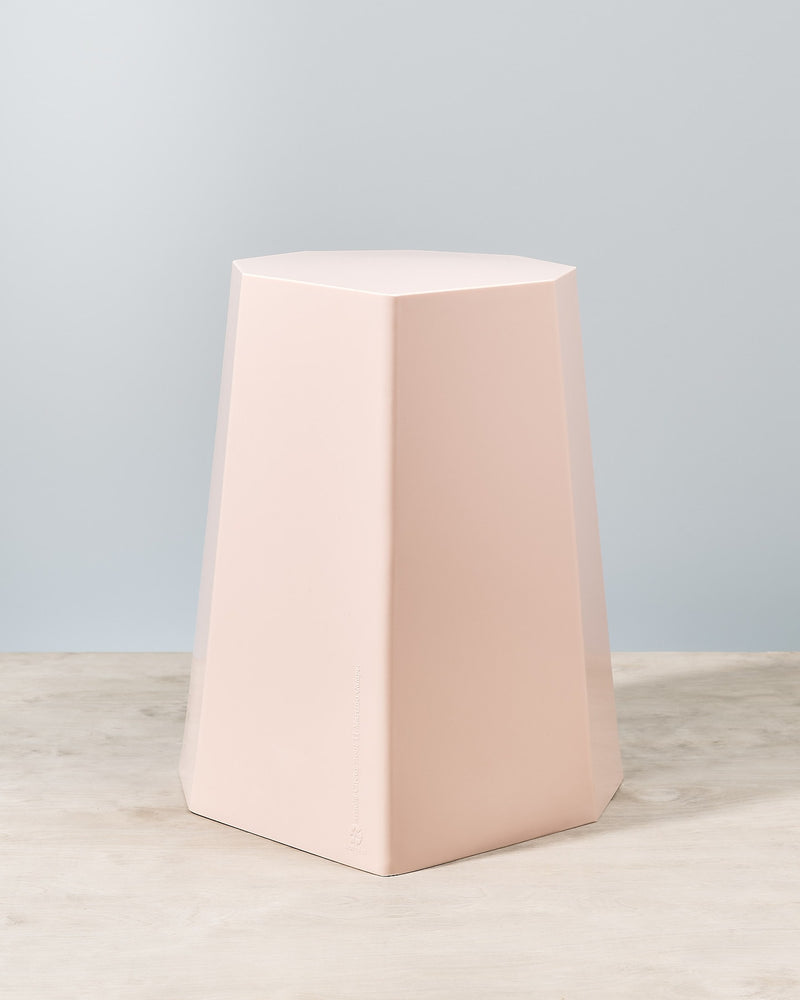 An Arnold Circus Stool - Pink by Martino Gamper on top of a wooden table.