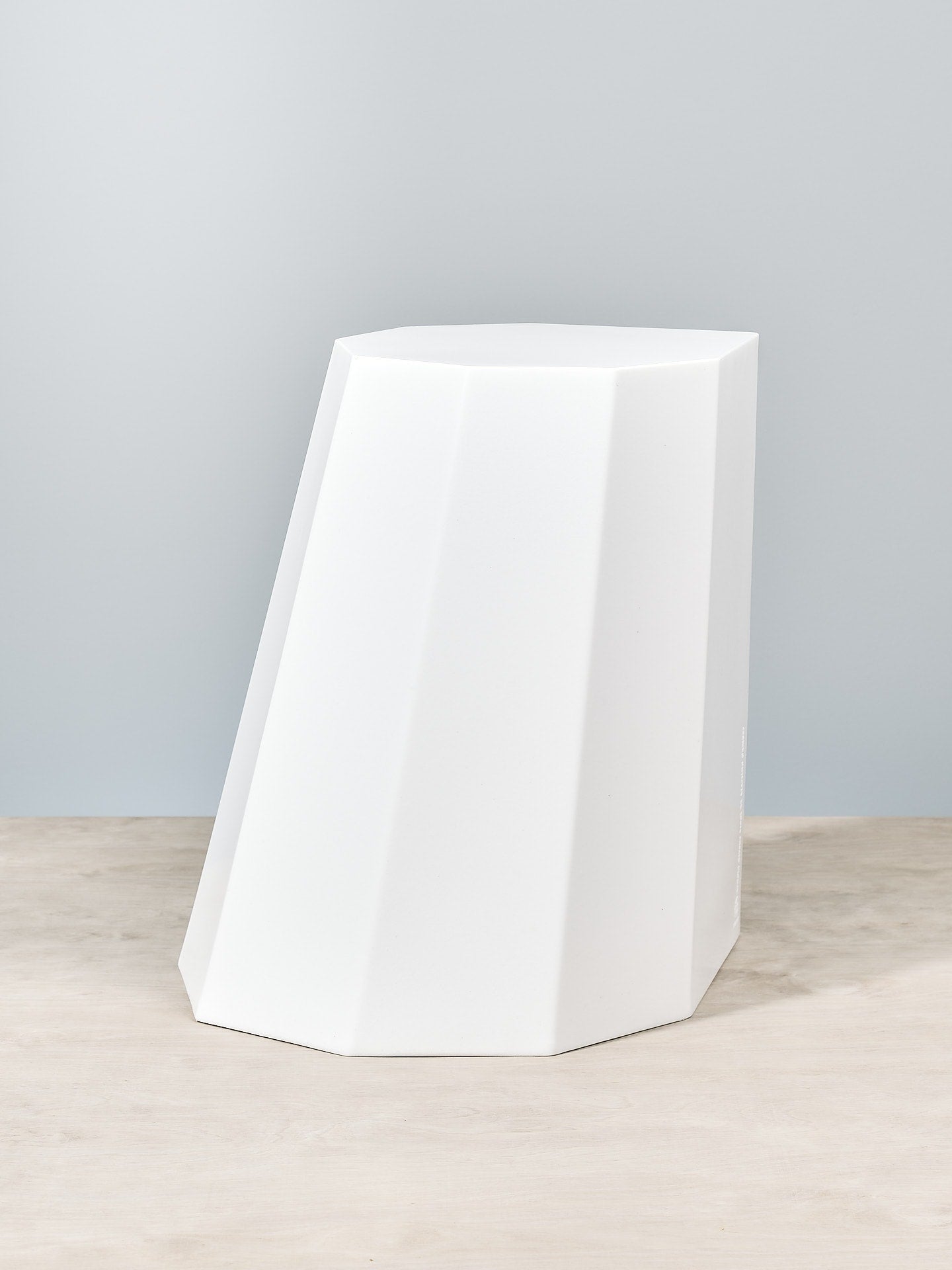 An Arnold Circus Stool - Chalk by Martino Gamper sitting on top of a wooden table.