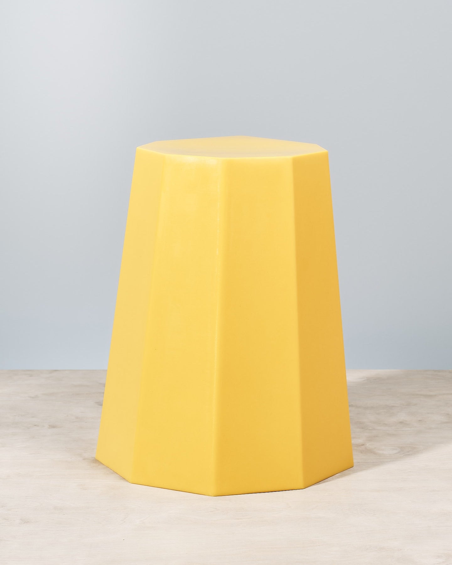 An Arnold Circus Stool – Yellow by Martino Gamper sitting on top of a wooden table.